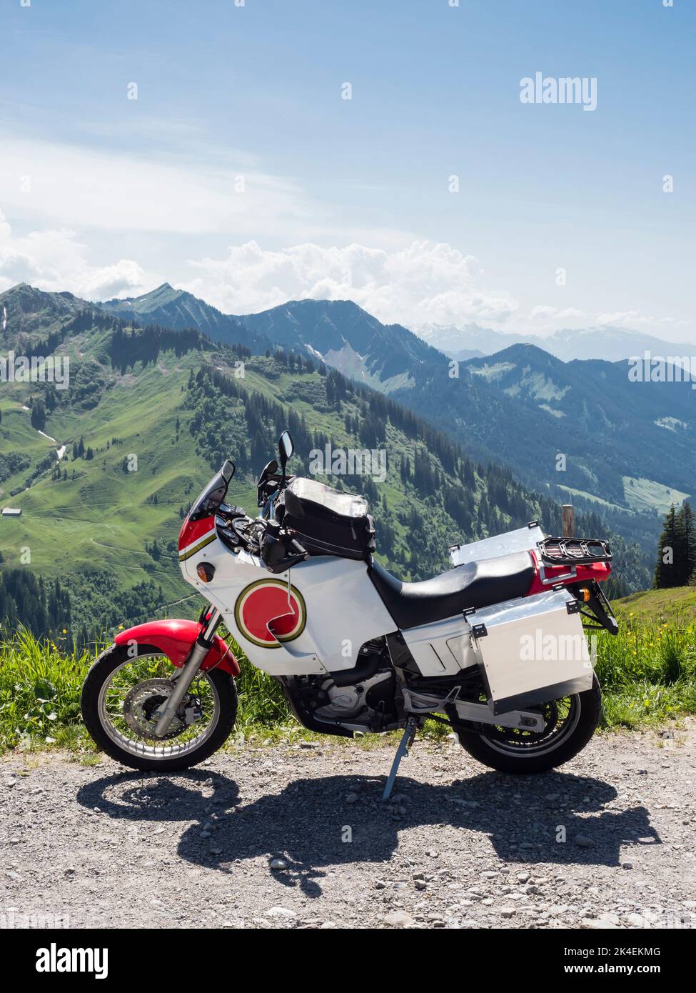 An adventure motorcycle with tank bag and big aluminum cases is parked at a mountain pass in the Swiss alps. Stock Photo