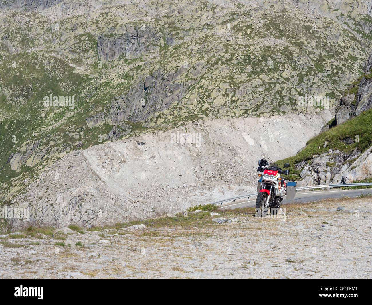 An adventure motorcycle is parked at a mountain pass in the Swiss alps. Stock Photo