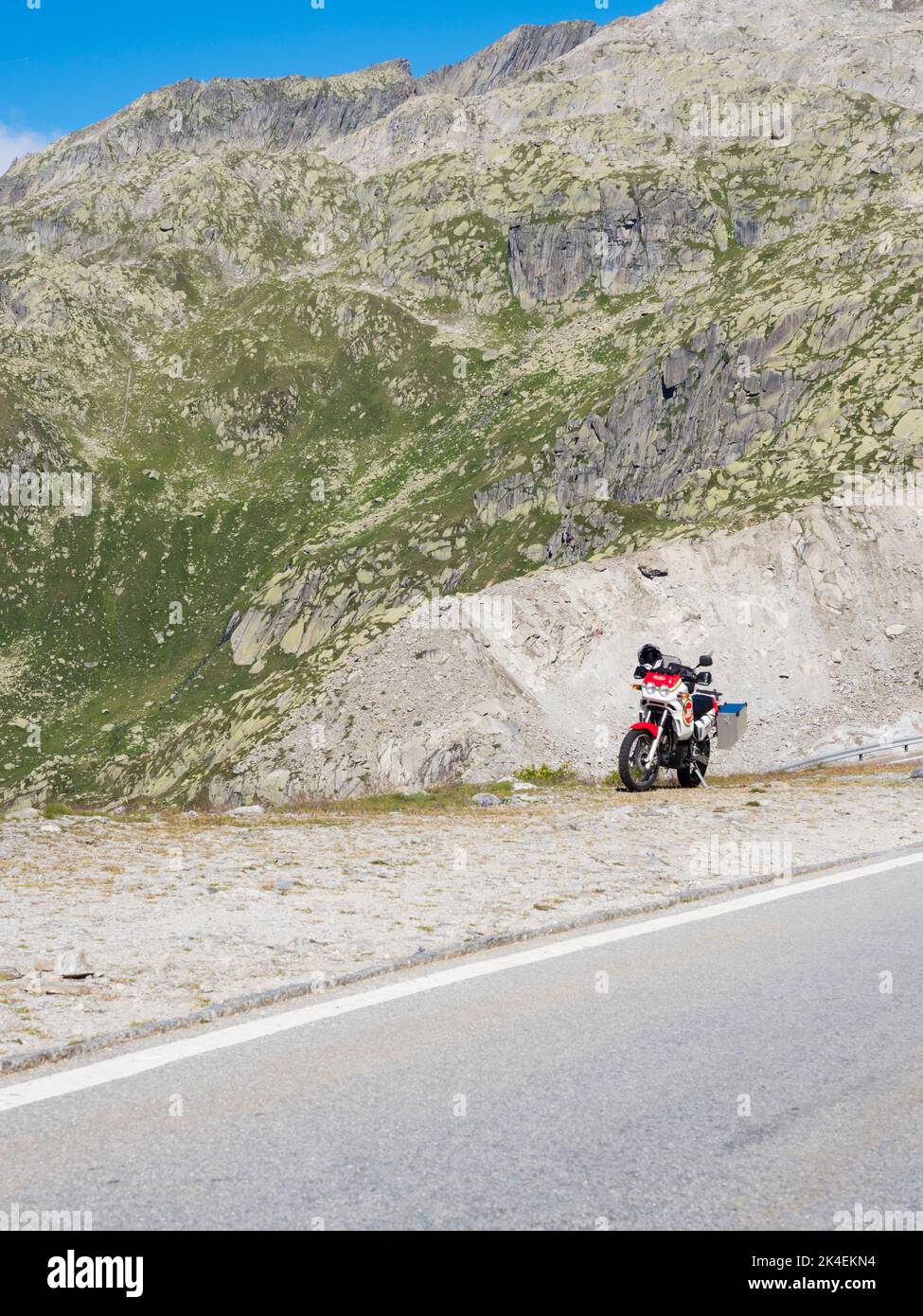 An adventure motorcycle is parked at a mountain pass in the Swiss alps. Stock Photo