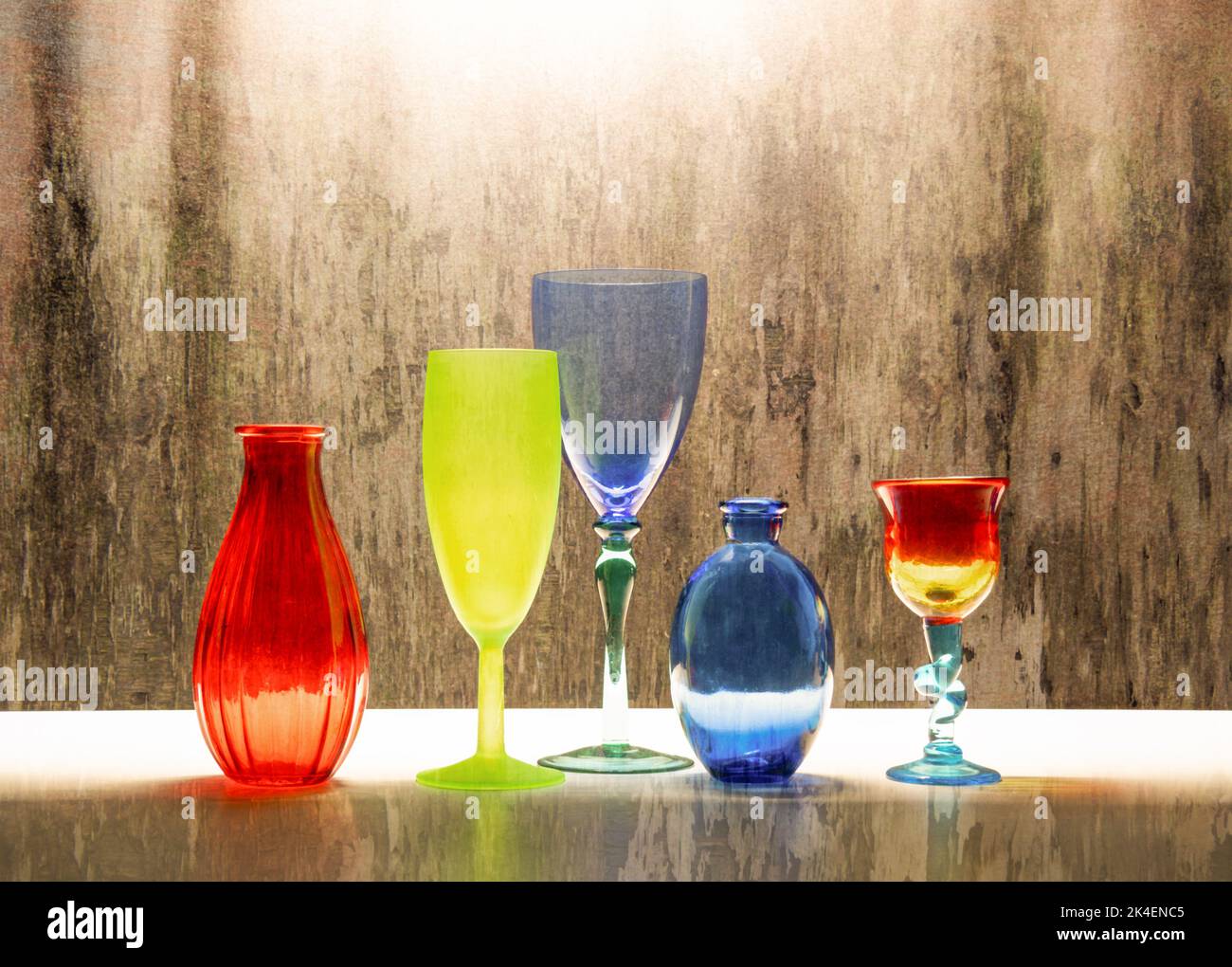 Colourful glassware still life with glasses, a bottle and a vase. Stock Photo