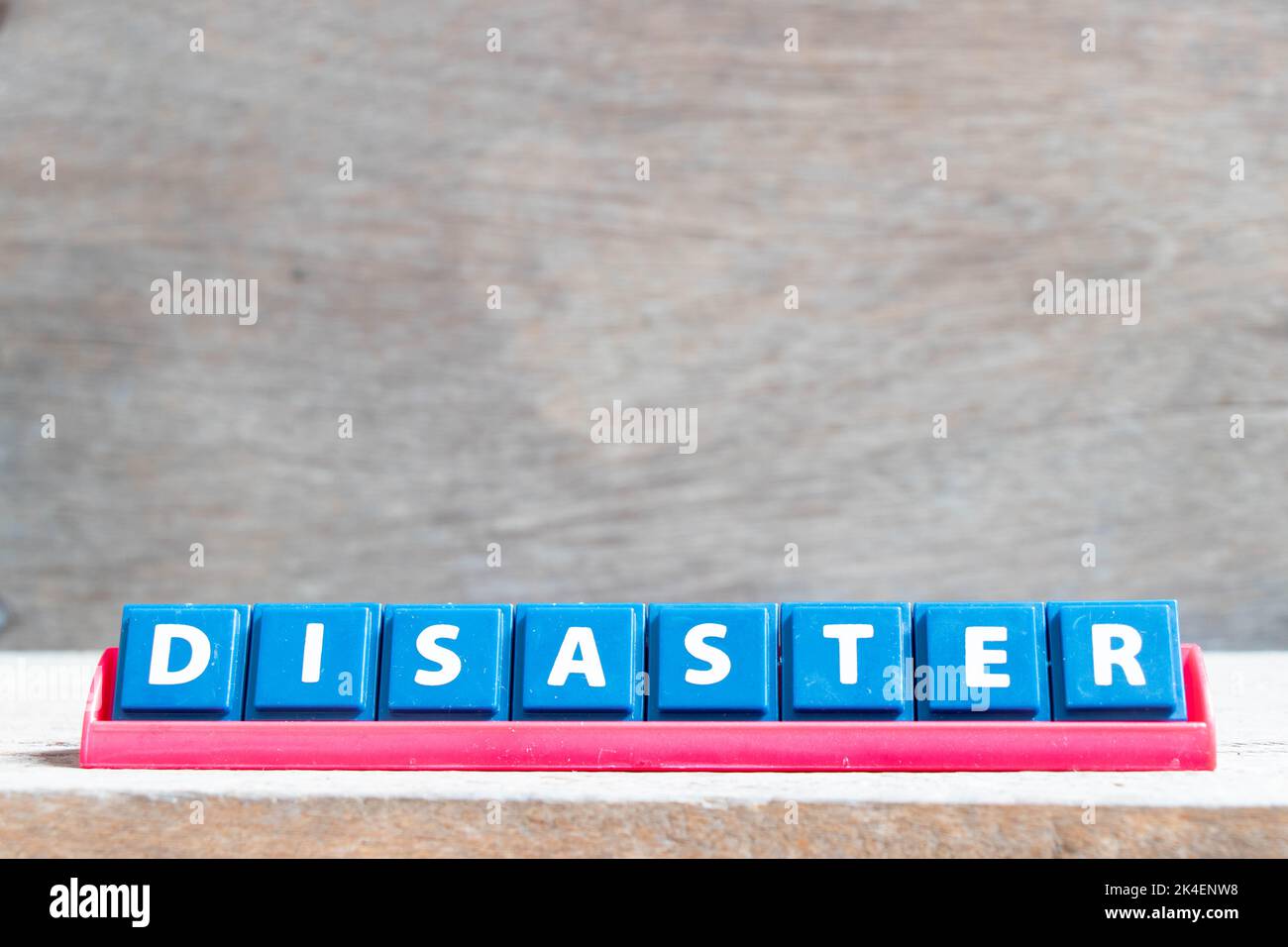 Tile alphabet letter with word disaster in red color rack on wood background Stock Photo