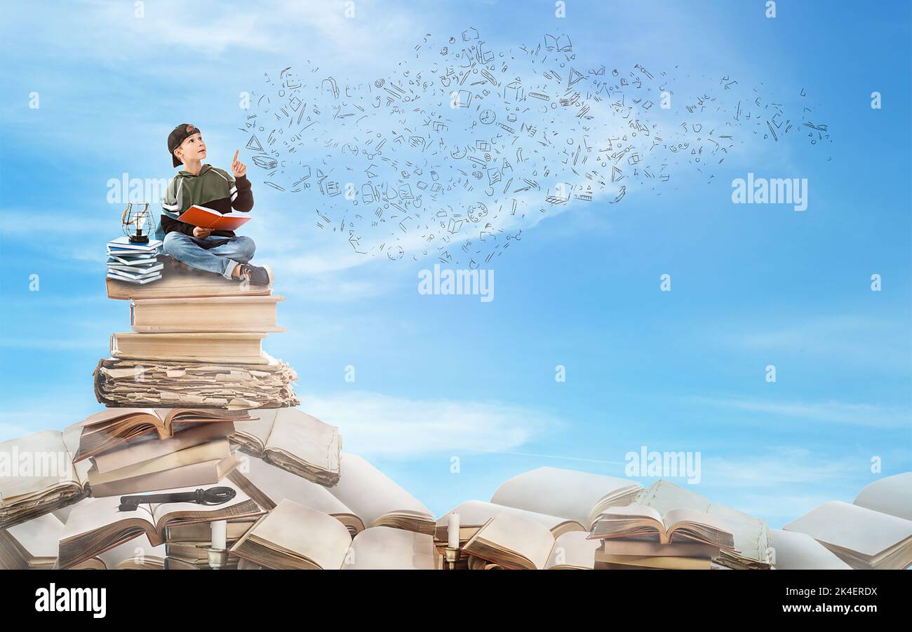 Cute little boy sitting on stack of books in blue sky Stock Photo - Alamy