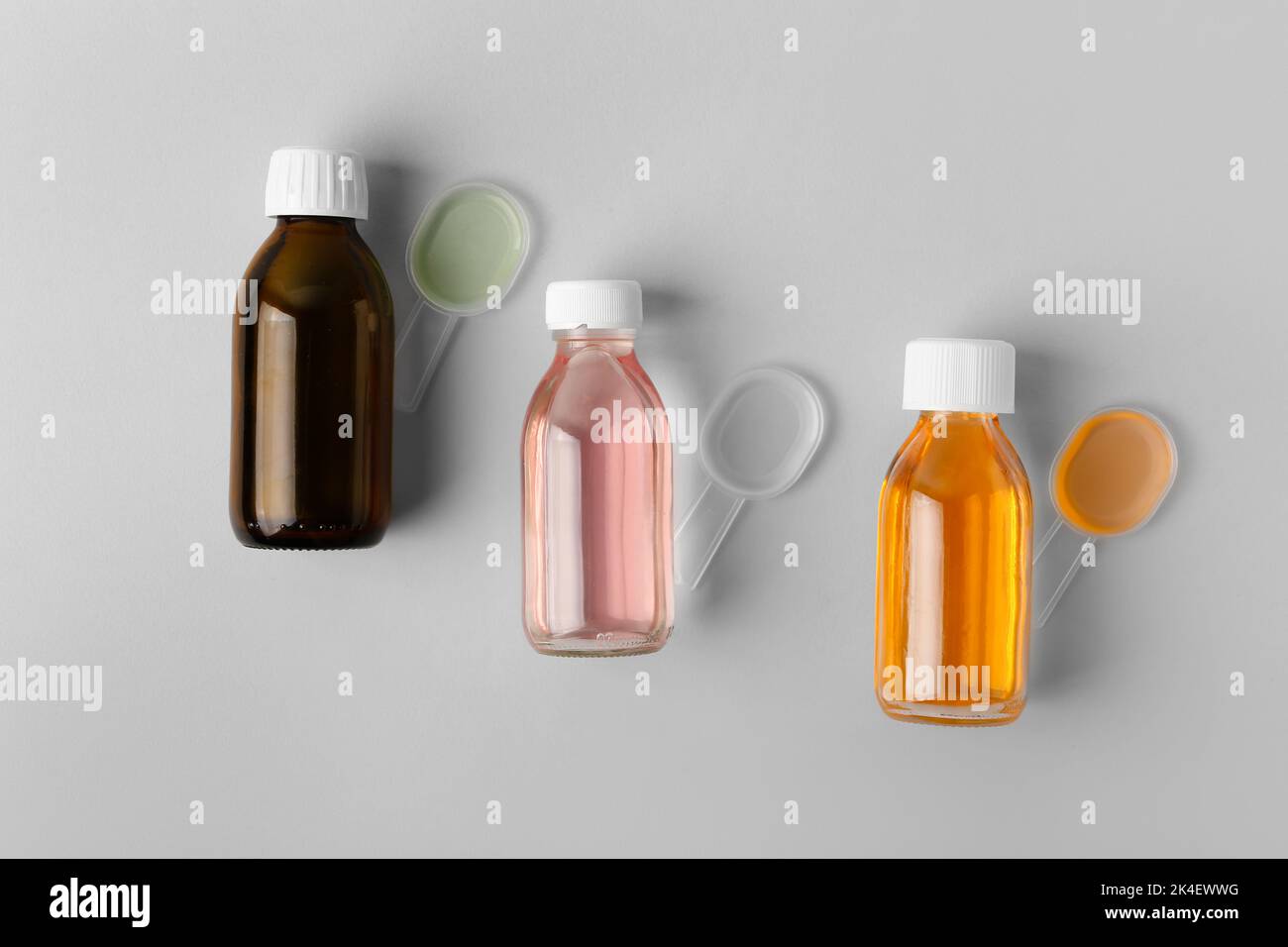 Bottles and spoons of cough syrup on grey background Stock Photo Alamy