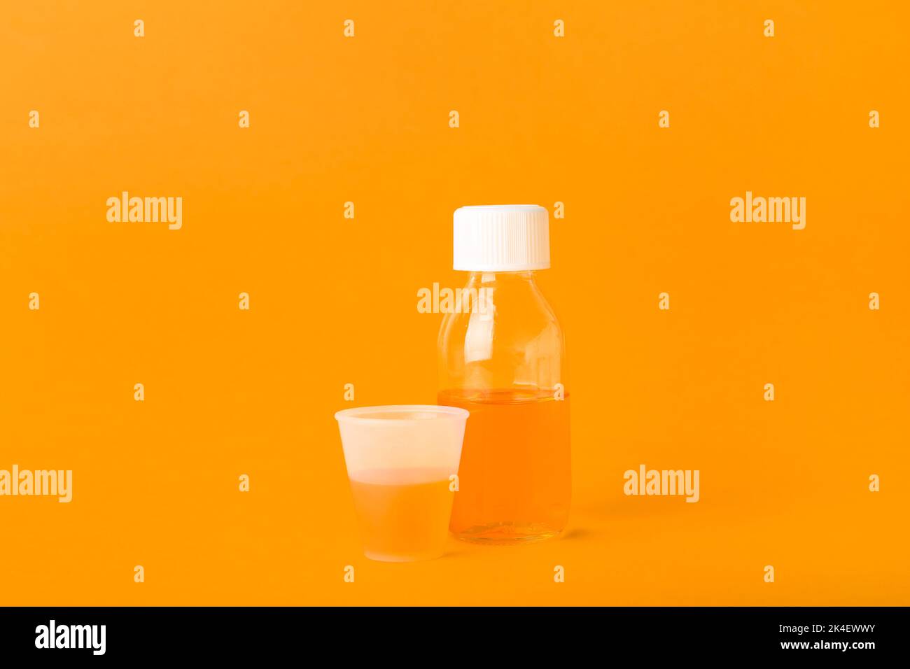 Bottle of cough syrup and cup on orange background Stock Photo Alamy