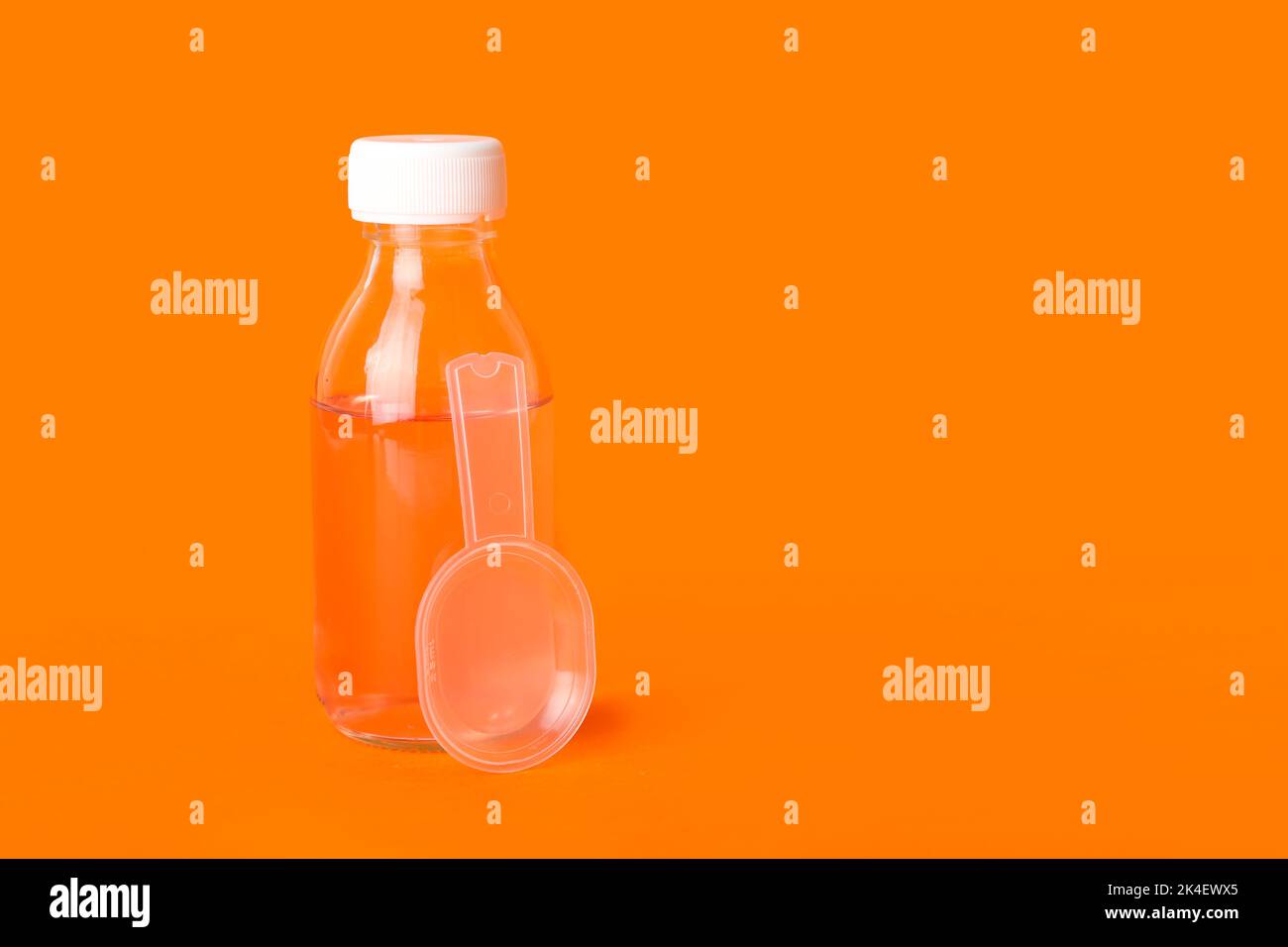 Bottle of cough syrup and spoon on orange background Stock Photo Alamy