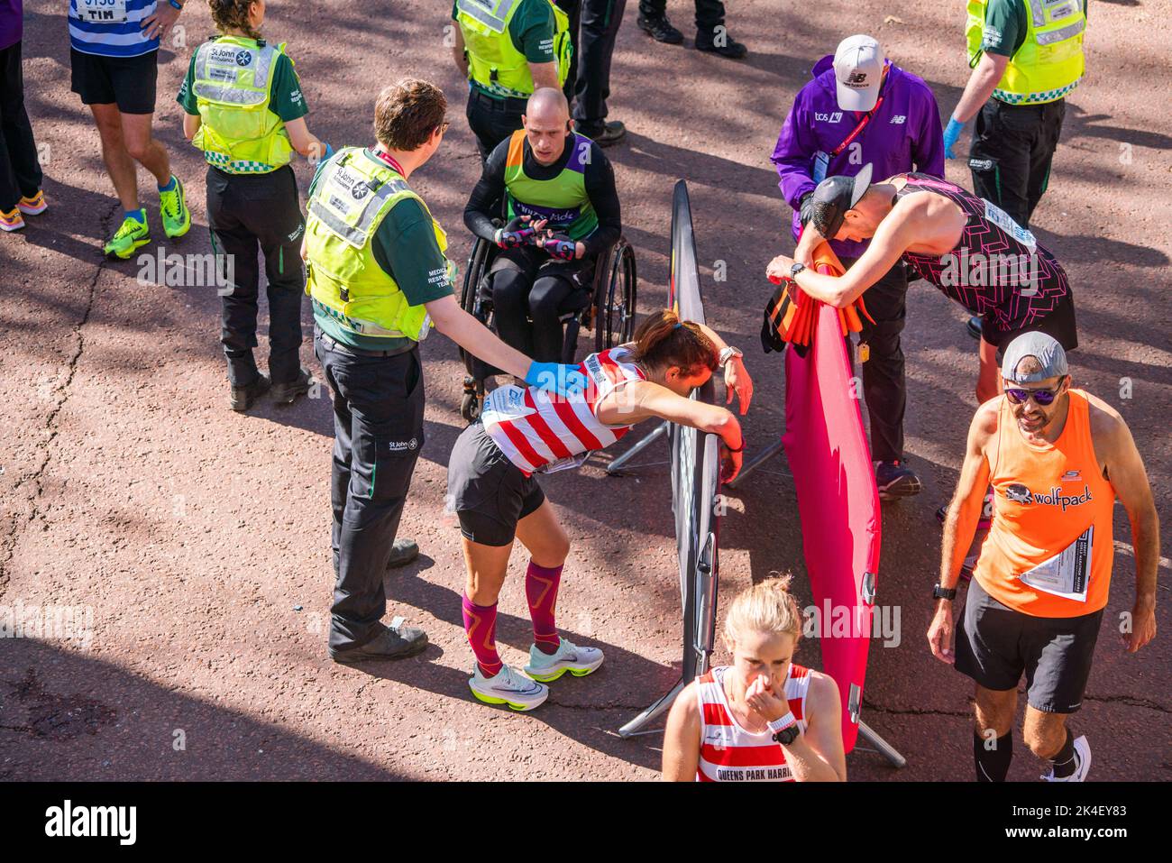 London UK. 2 October 2022 . A marathon runner  is helped by paramedics after crossing the finishing line at The Mall .More than  40,000 athletes including  elite  runners, club runners and fun runners   take  part in the London Marathon sponsored by TCS Tata Consultancy Services over a 26.2 mile course.Credit: amer ghazzal/Alamy Live News. Stock Photo