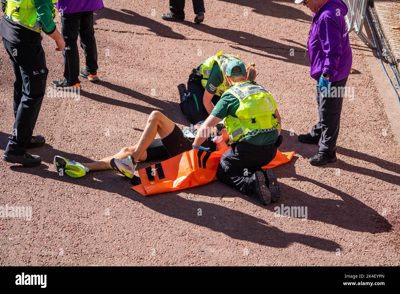London UK. 2 October 2022 . A marathon runner  is attended  by paramedics after crossing the finishing line at The Mall .More than  40,000 athletes including  elite  runners, club runners and fun runners   take  part in the London Marathon sponsored by TCS Tata Consultancy Services over a 26.2 mile course.Credit: amer ghazzal/Alamy Live News. Stock Photo