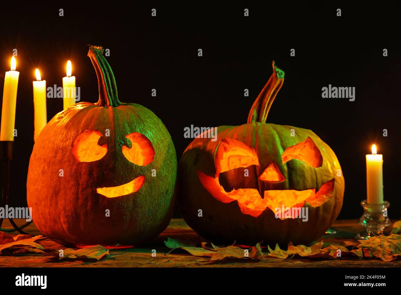 Carved Halloween pumpkins with burning candles and fallen leaves on ...