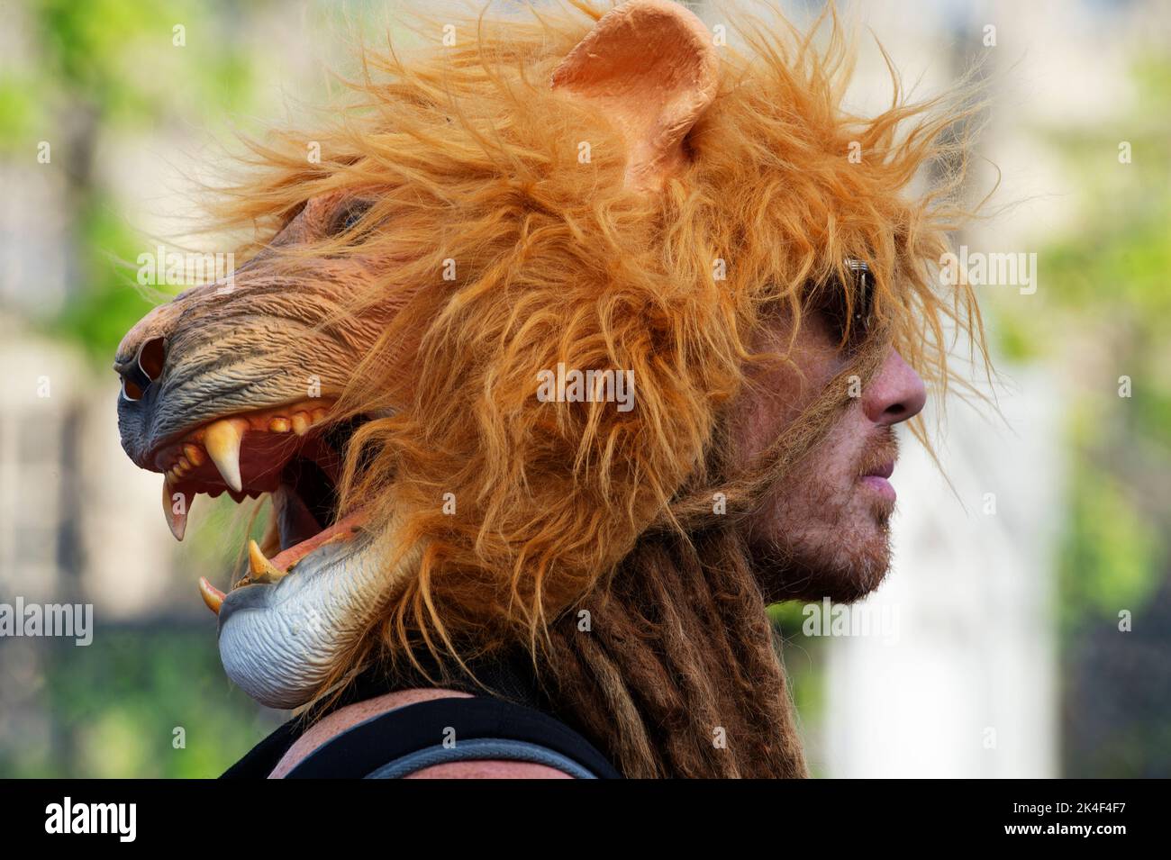 London. People protest against the oil industry and the cost of living crisis. A man with dreadlocks wears a lion mask on his head. Stock Photo