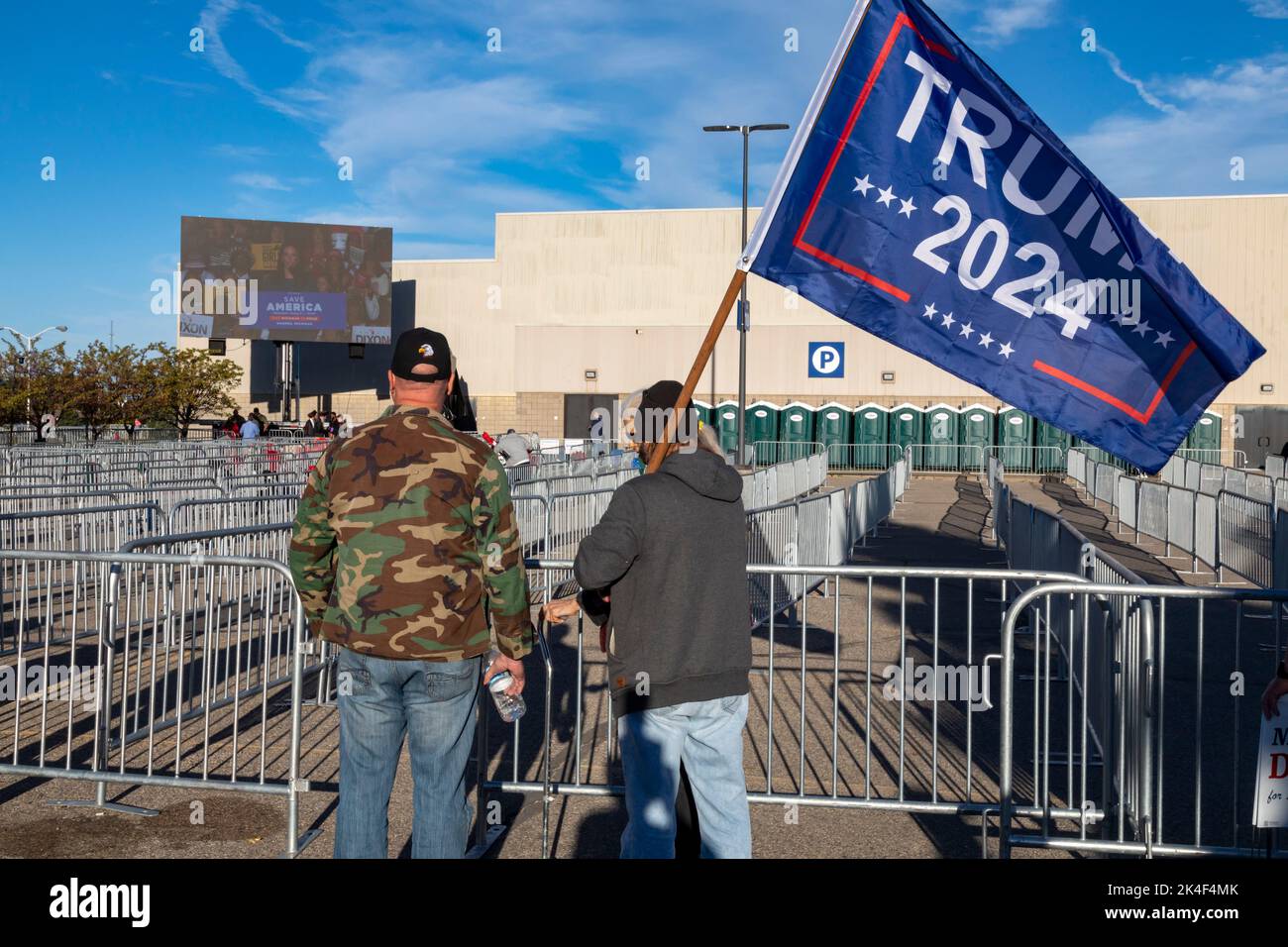 Warren, Michigan, USA. 1st Oct, 2022. Two Donald Trump supporters outside a rally where the former president campaigned for the candidates he has endorsed in the 2022 Michigan general election. He is supporting Tudor Dixon, who is shown speaking at the rally on the screen at left, for Michigan governor. Credit: Jim West/Alamy Live News Stock Photo