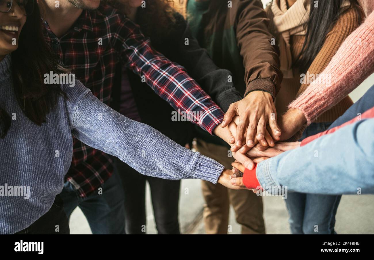 Happy young friends having fun stacking hands together outdoor - Youth people millennial generation concept Stock Photo