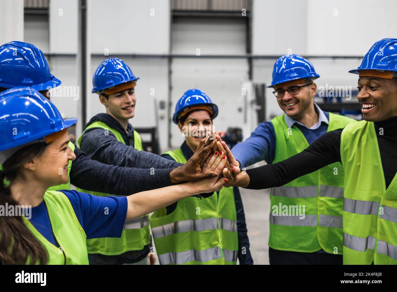 Team of multiracial engineers stacking hands together inside robotic factory - Tech industry concept Stock Photo