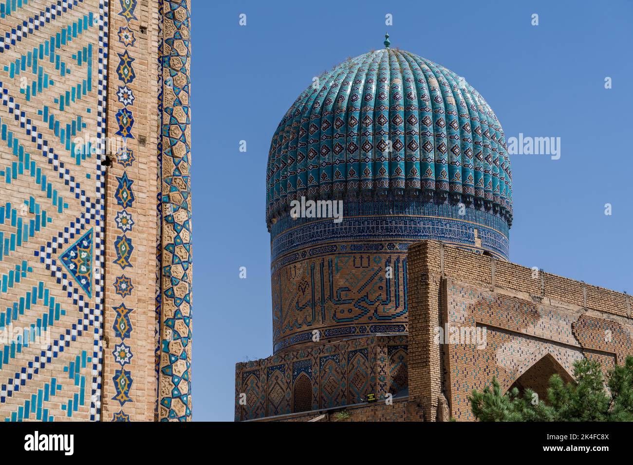 Zoom of Blue tile dome and wall of Bibi-Khanym Mosque in bright blue sky in Samarkand. Stock Photo