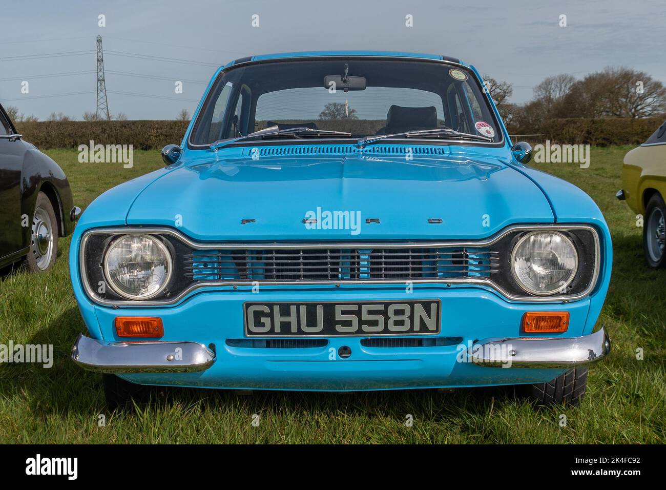 A front view of a 1974 light blue Ford Escort Mk 1 parked on grass at a meet of classic car clubs Stock Photo