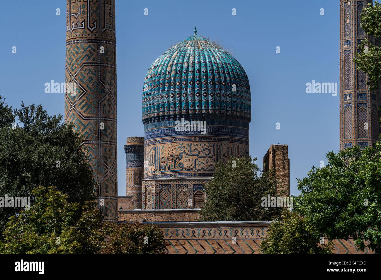 Zoom of Blue tile minaret dome and wall of Bibi-Khanym Mosque in bright blue sky in Samarkand. Stock Photo