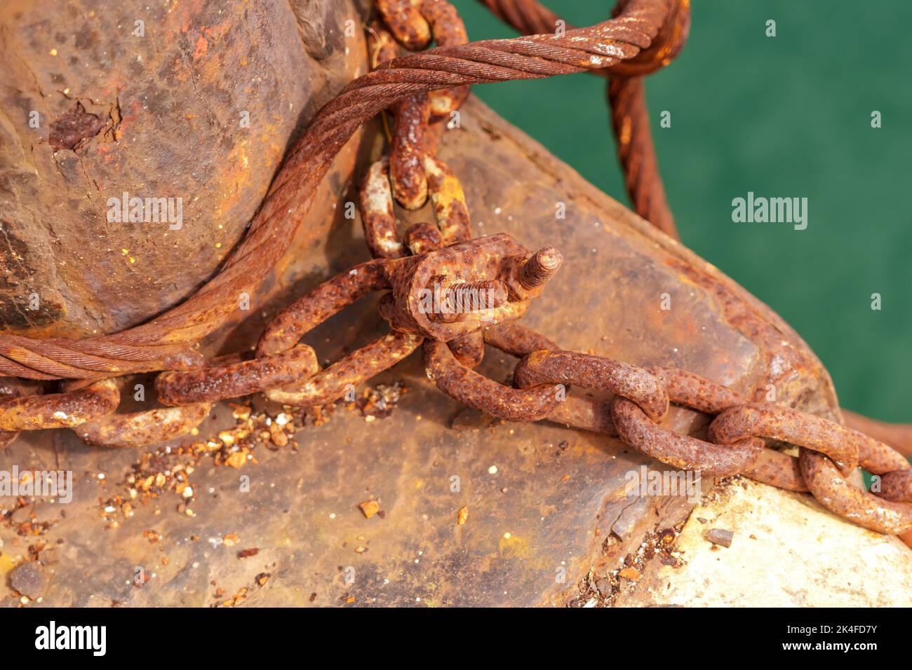 Old abandoned anchor chain with rust and iron cleat, hawser on a post