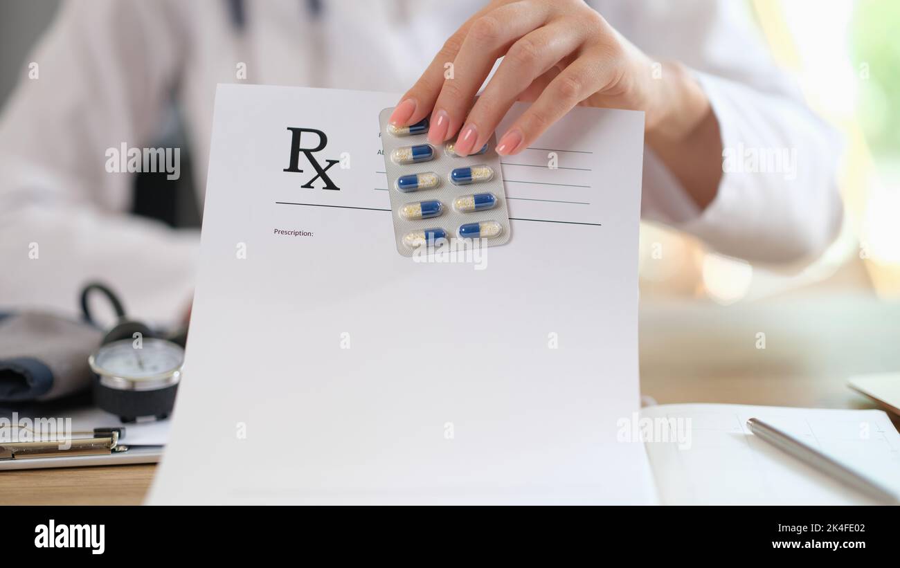 Medical doctor holds a blister of pills and writes prescription to patient closeup Stock Photo