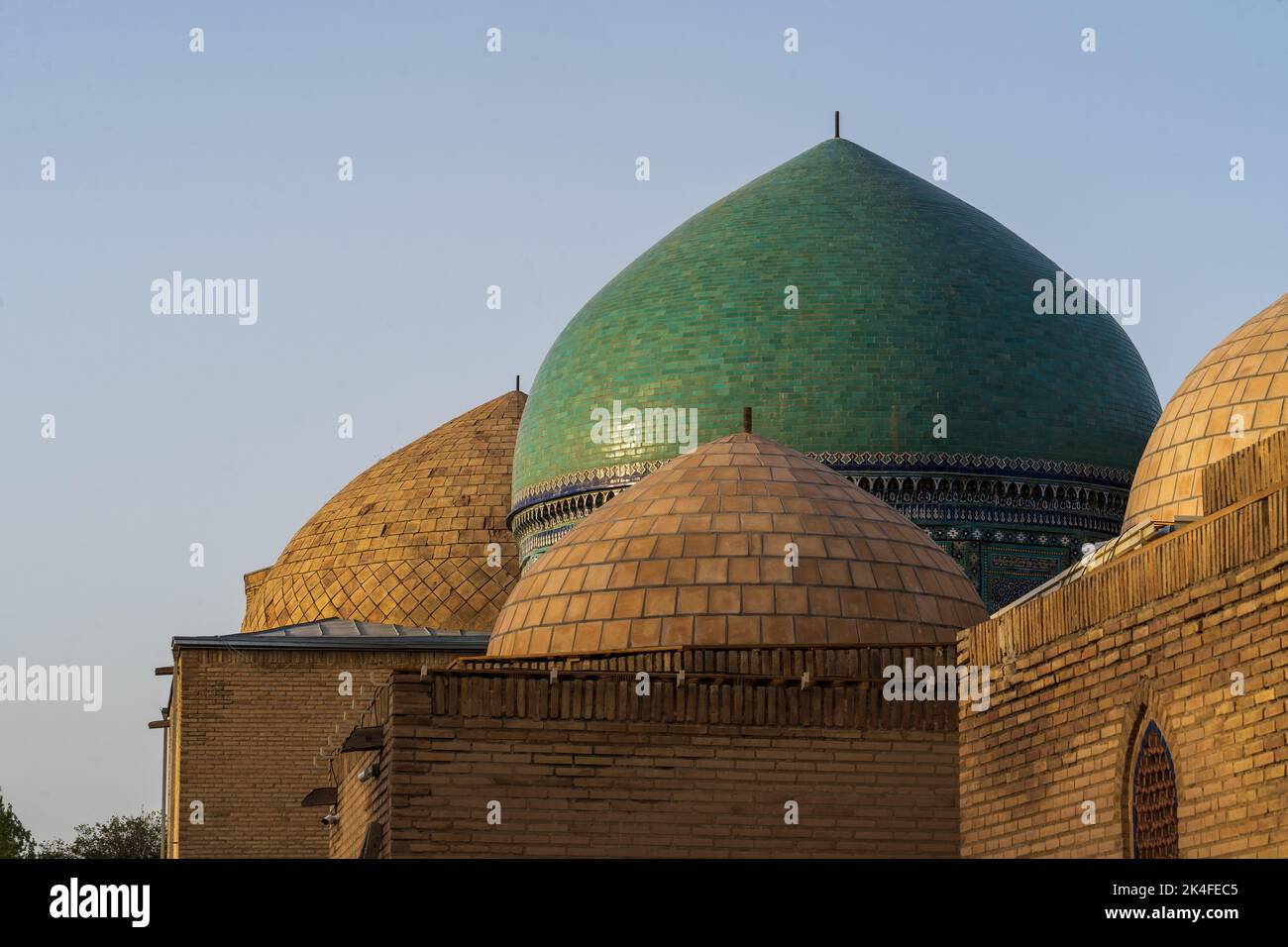 Green emerald dome and blue tiles of the Shah-i-Zinda mausoleum complex at sunset, Samarkand Stock Photo