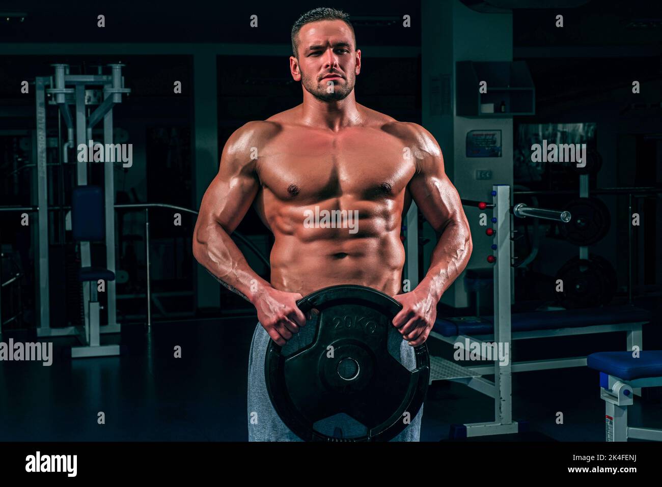 Powerlifter with heavy weight disk in sport gym. Bodybuilder training