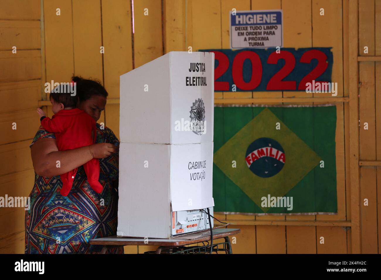 A woman holds a baby while casting her vote at a polling station set up on a floating school on the Negro river, in the Catalao Community, Brazil October 2, 2022. REUTERS/Bruno Kelly Stock Photo