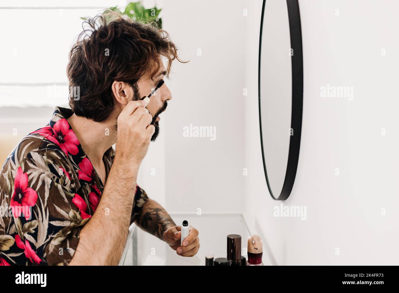 Young man applying eyelashes sitting at a dressing table Stock Photo