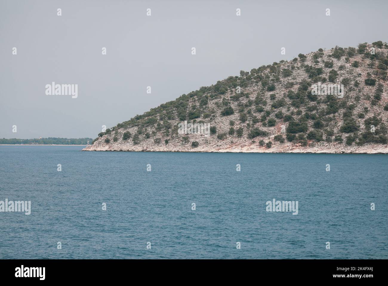 Small Greek island covered with small vegetation during a sunny summer day. Stock Photo