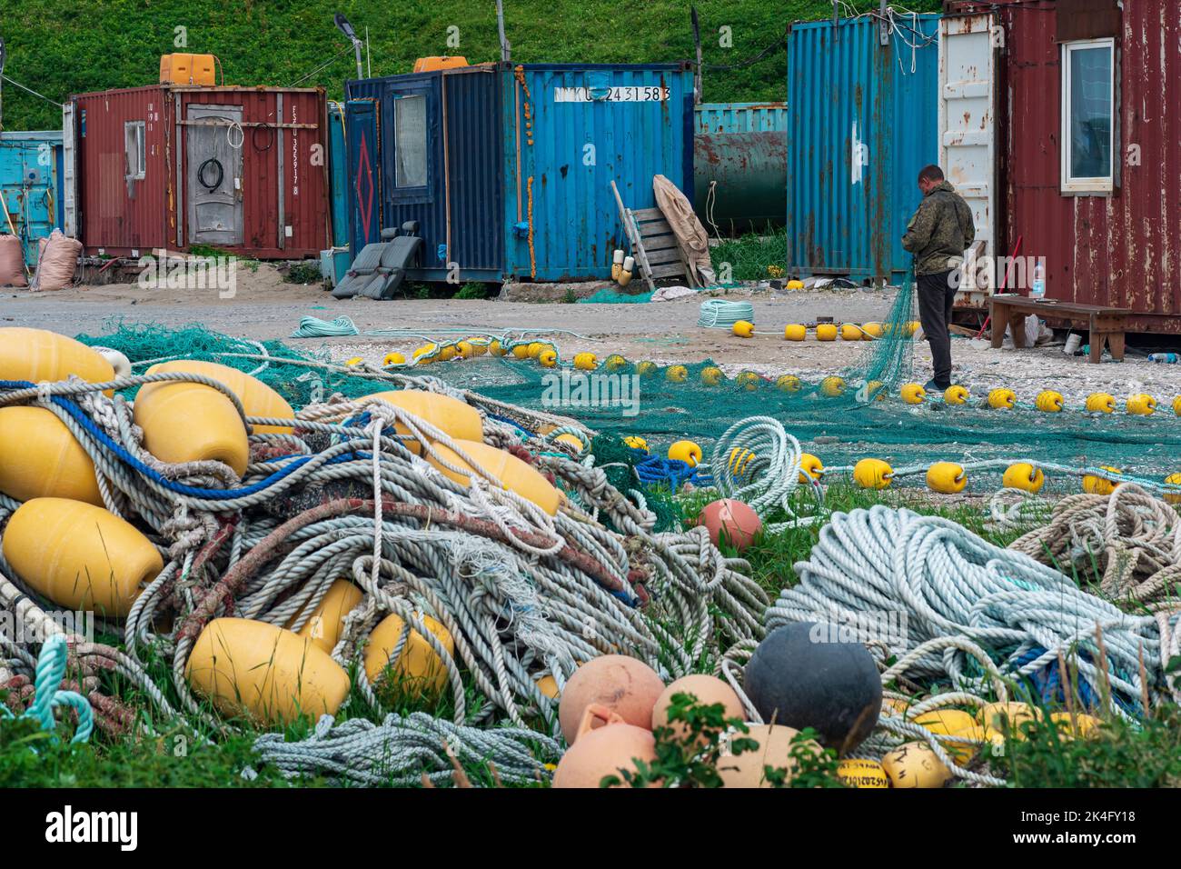 Lagunnoe, Russia - August 01, 2022: fisherman checks and repairs industrial fishing nets on the shore at a fishing base Stock Photo
