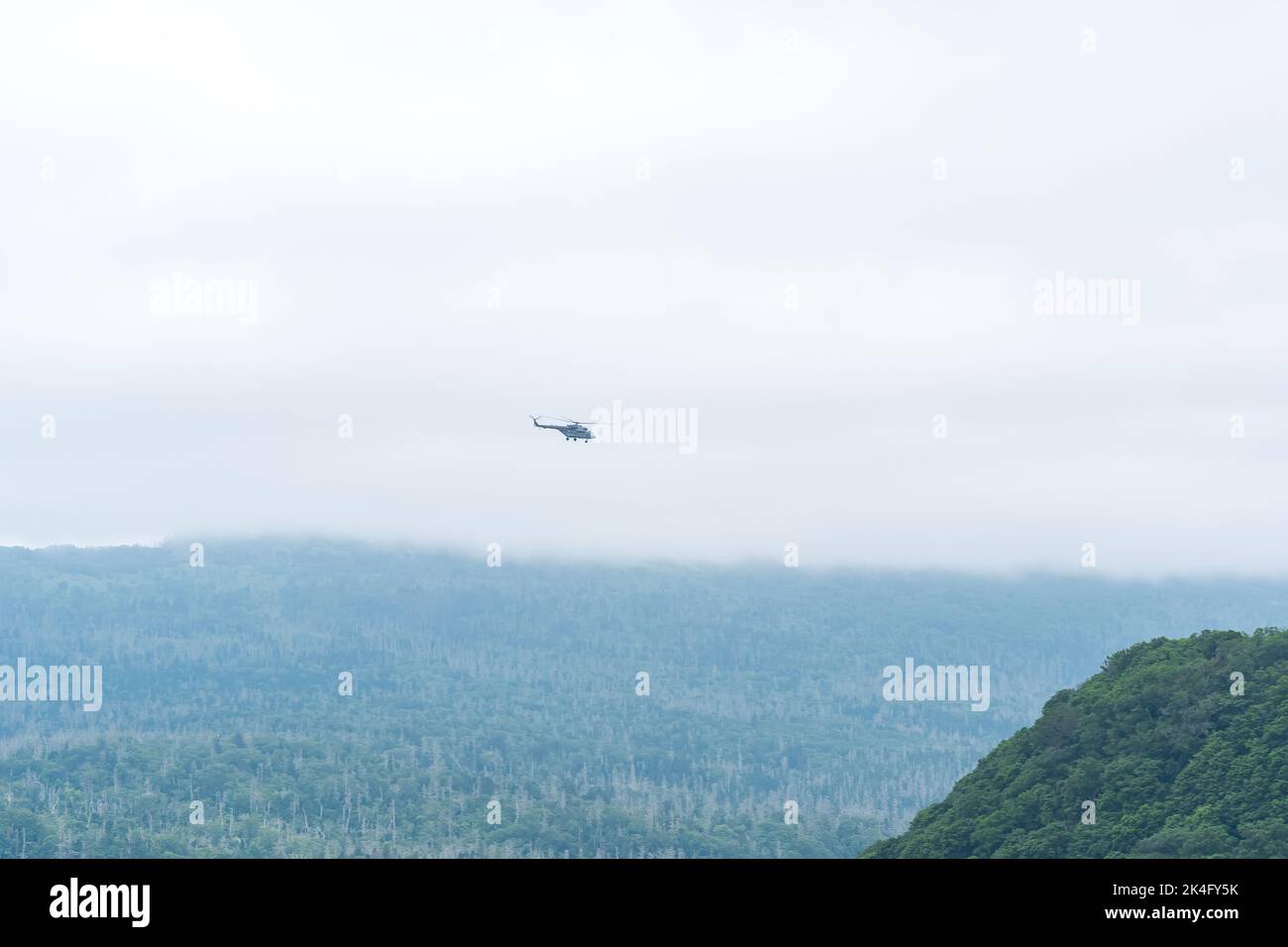 cloudy landscape with distant helicopter over misty hills Stock Photo