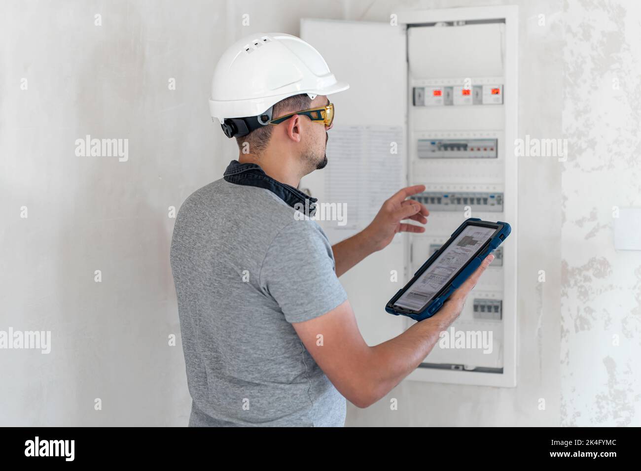 Electrical technician looking focused while working in a switchboard with fuses. Stock Photo