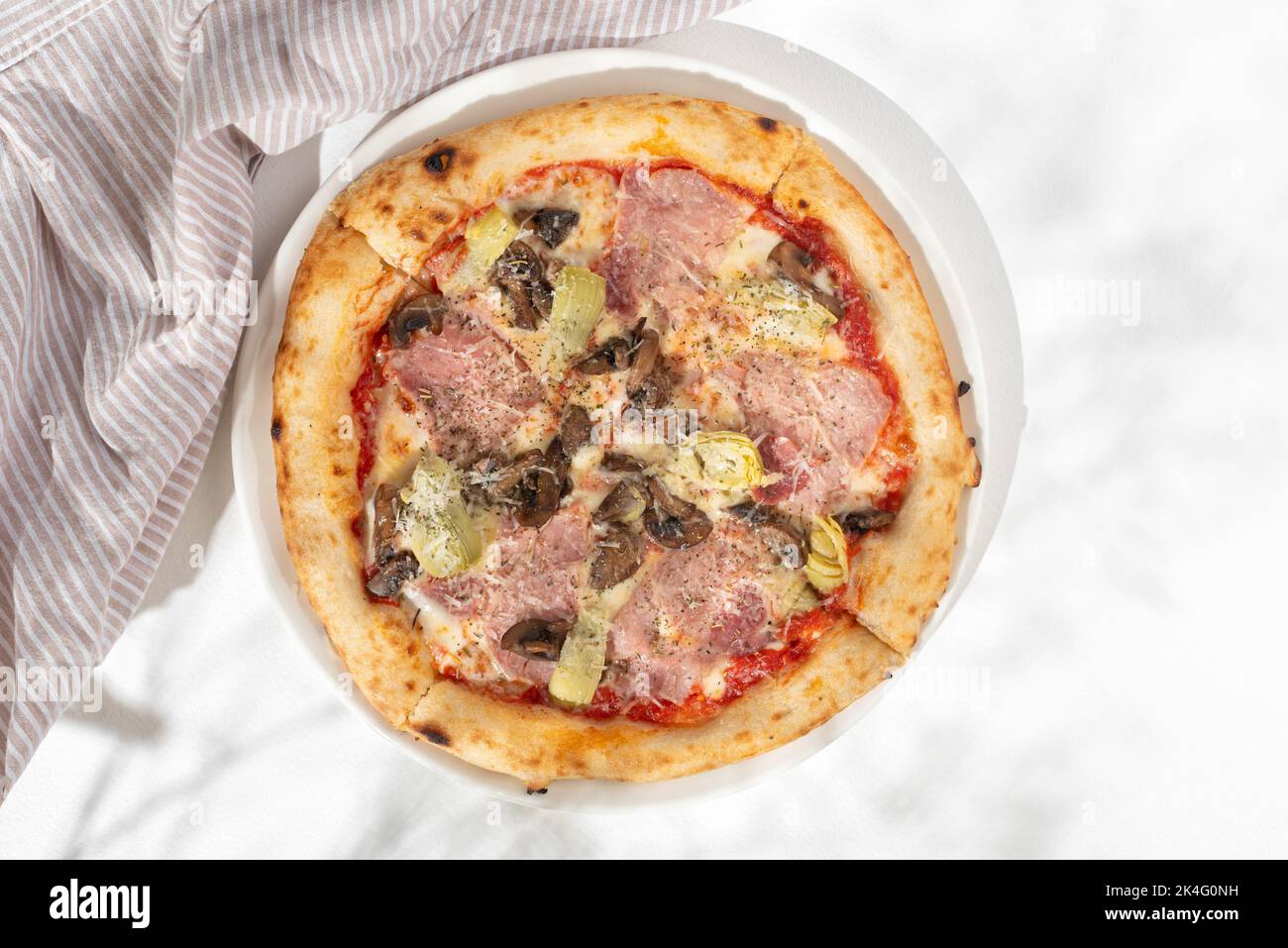Pizza capricciosa with white mushrooms, ham, artichoke, tomatoes