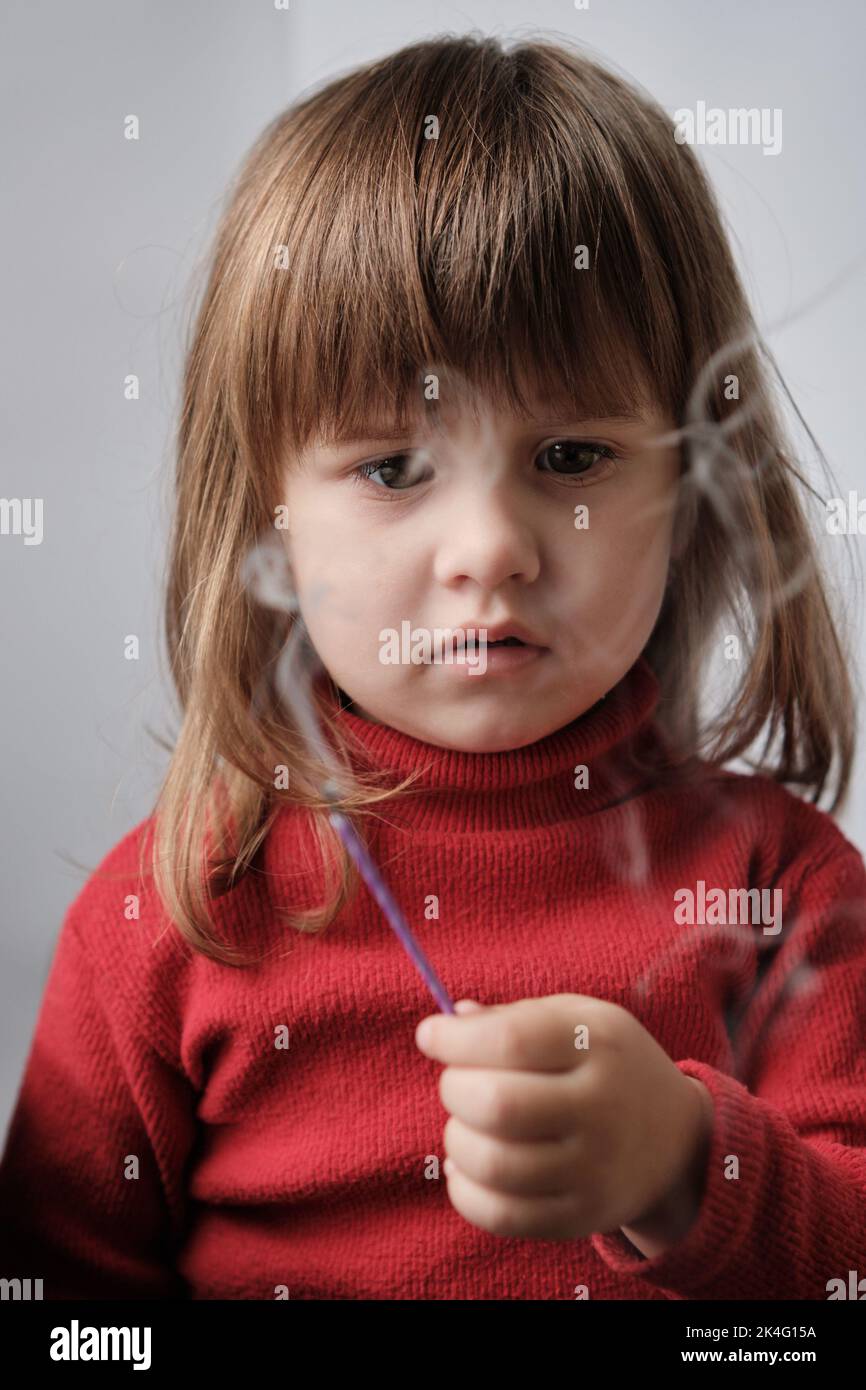 Portrait of little girl blowing out burning candle. Child holding