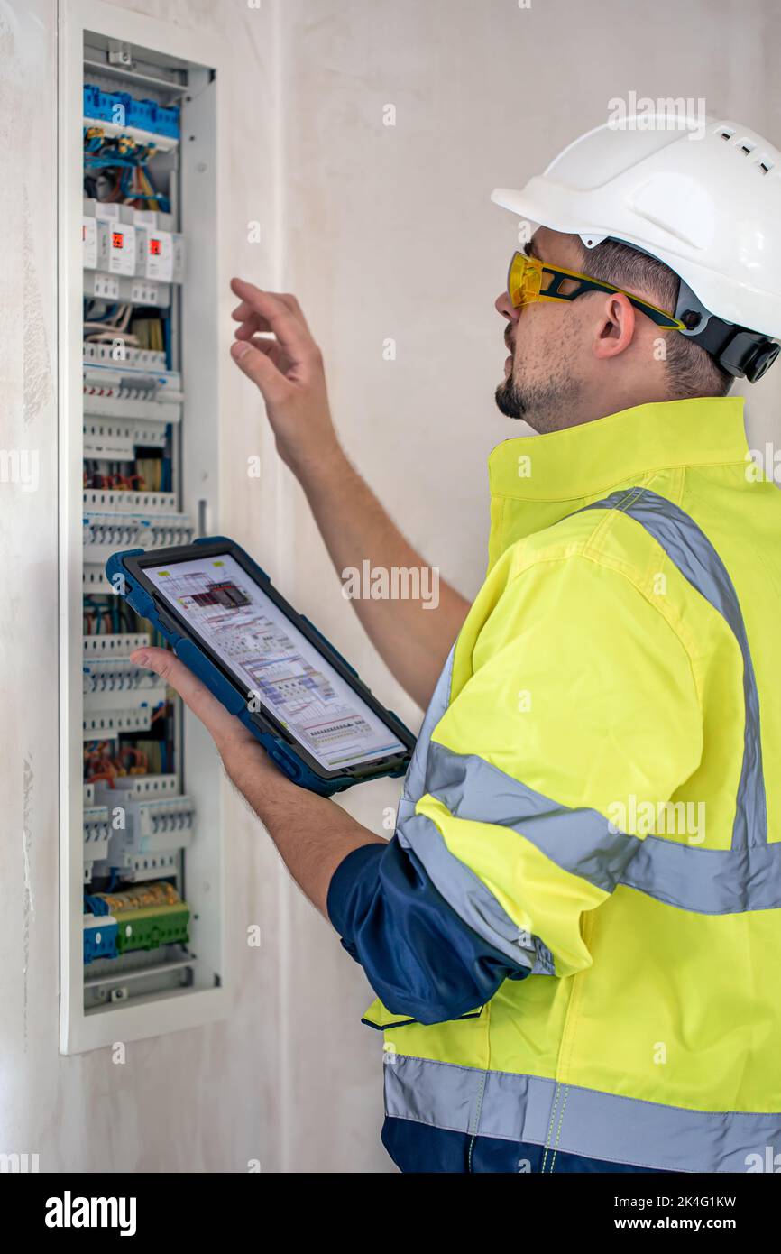 Electrical technician looking focused while working in a switchboard with fuses. Stock Photo