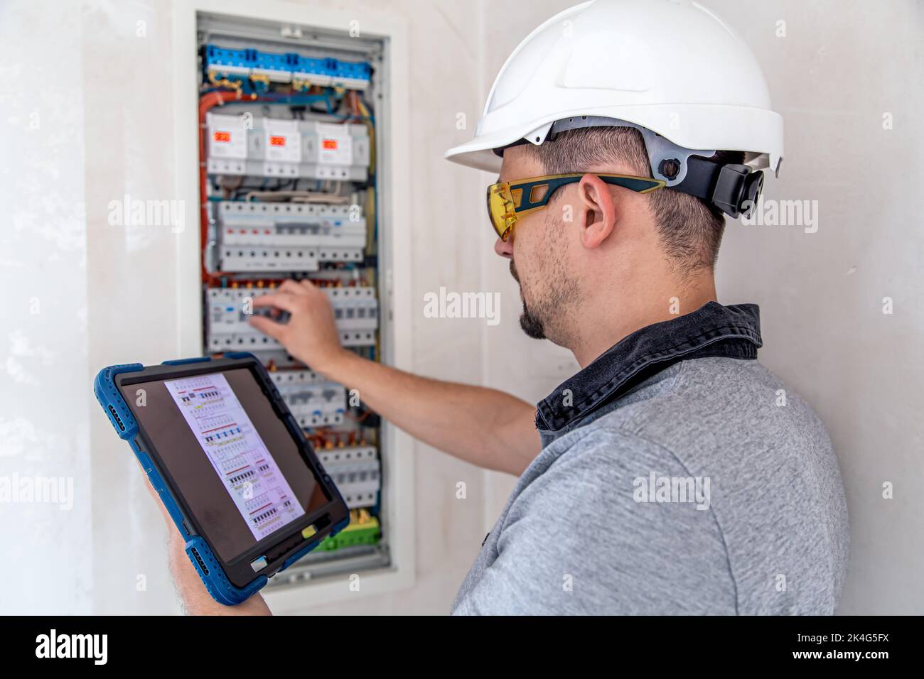 Electrical technician looking focused while working in a switchboard with fuses. Stock Photo