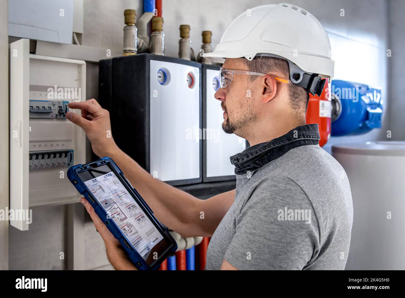 Electrical technician looking focused while working in a switchboard with fuses. Stock Photo