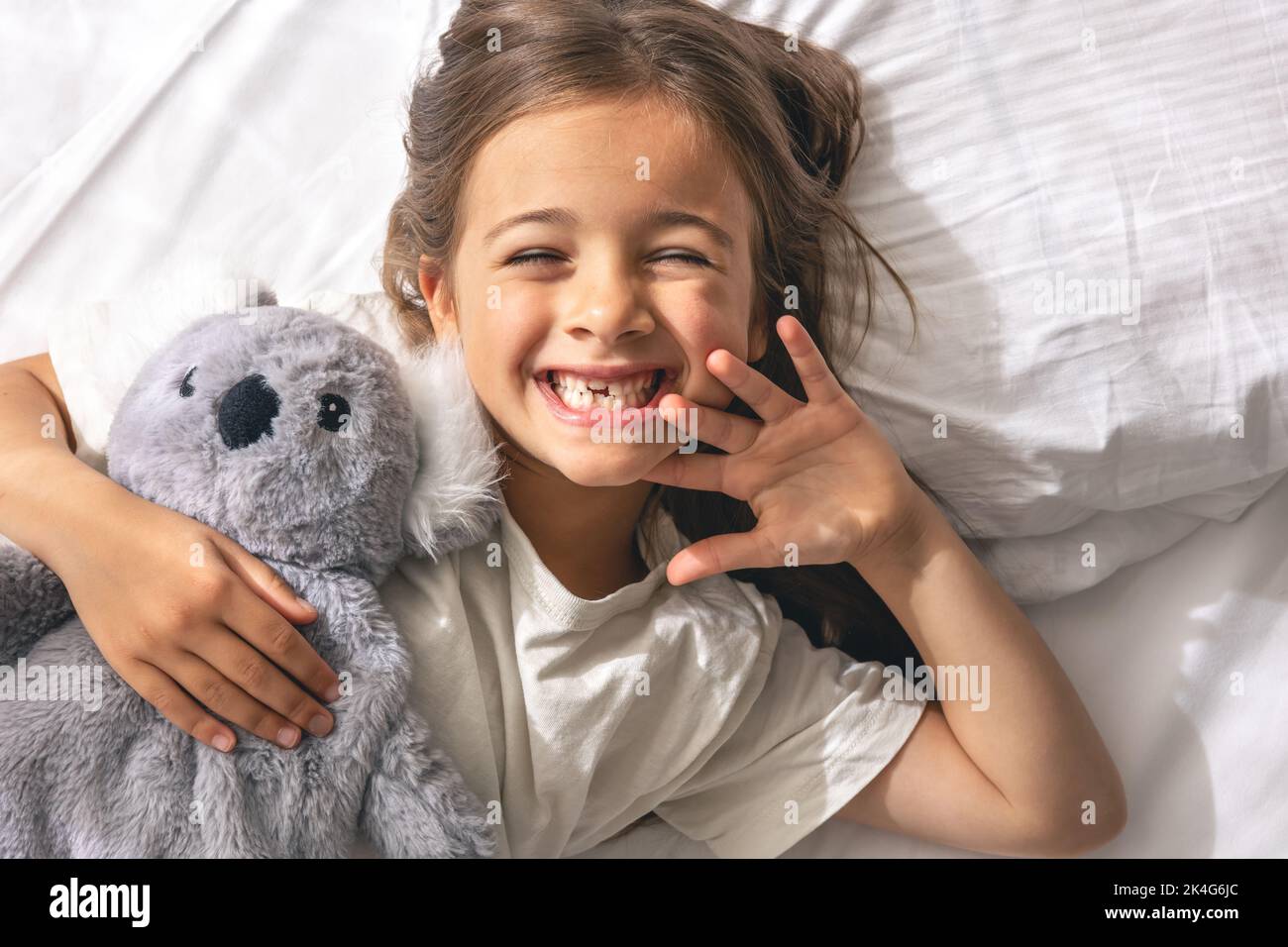 Cute little girl with her favorite soft toy in bed in the morning Stock