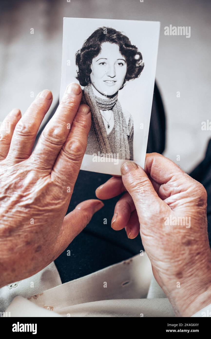 CIRCA 1970: Elderly woman hands holding vintage, black and white photo of the young woman. Passing of time concept Stock Photo