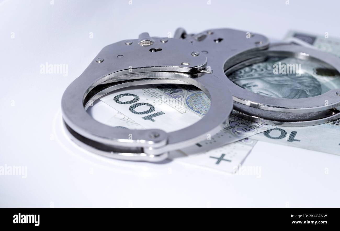 Police handcuffs and banknotes in Polish currency. The concept of economic crime in Poland. Banknotes of Polish zlotys. Stock Photo
