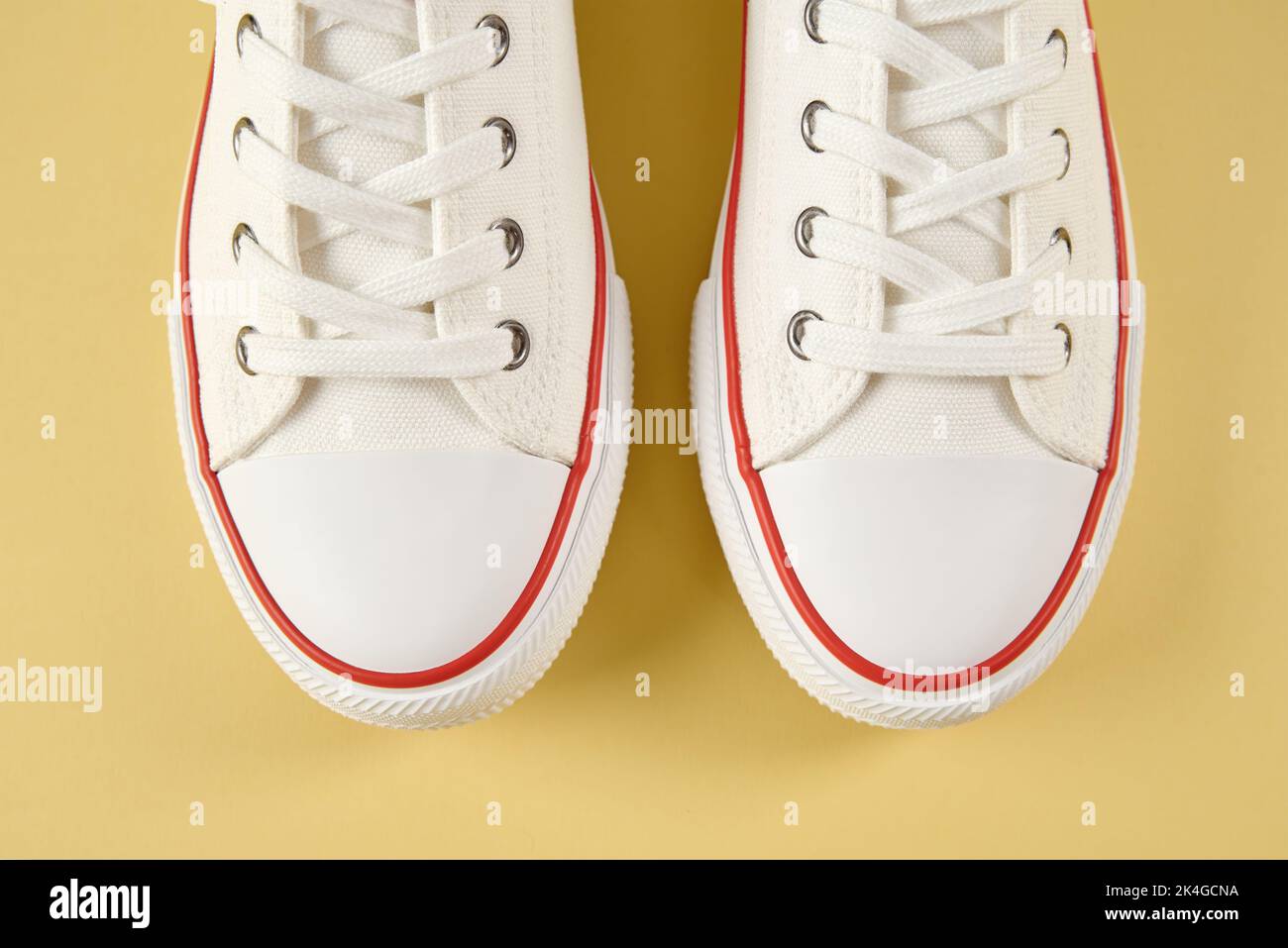 Pair of trendy shoes on yellow background, flat lay top view. Sport sneakers with copy space, Summer footwear concept Stock Photo