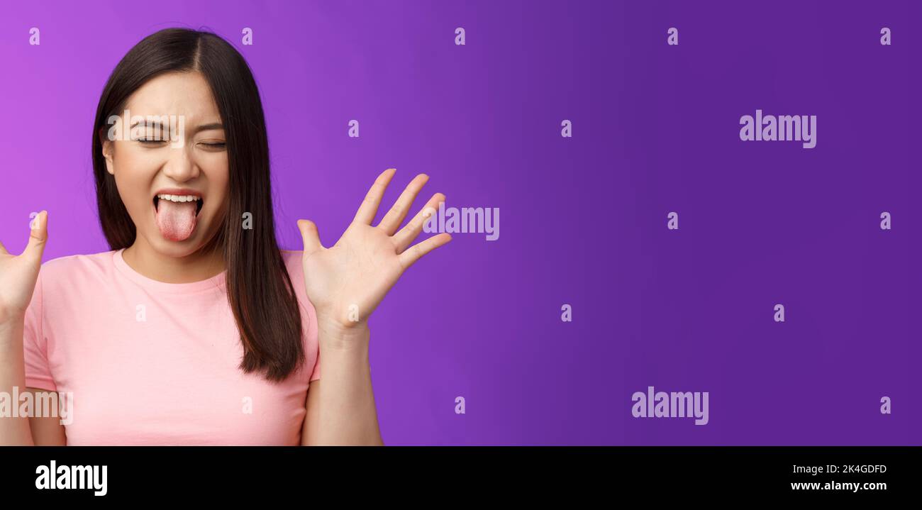 Close-up silly moody asian girl complaining act immature and bothered, raise hands unsatisfied show tongue aversion disgust, close eyes, react Stock Photo