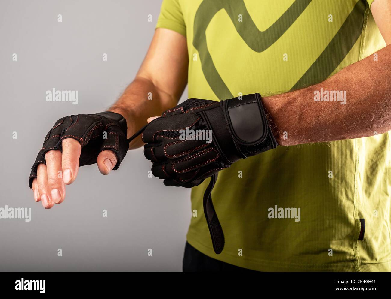 Wearing, putting on sport workout gloves close up for palm and wrist protection in gym. photo Stock Photo