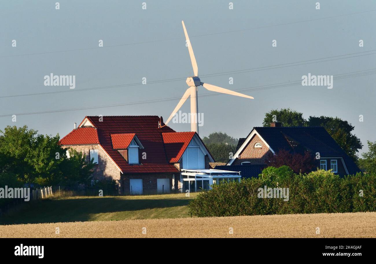 Kappeln, Germany. 12th Aug, 2022. 12.08.2022, Kappeln on the Schlei. A windmill for electricity generation stands behind residential houses near Kappeln. Credit: Wolfram Steinberg/dpa Credit: Wolfram Steinberg/dpa/Alamy Live News Stock Photo