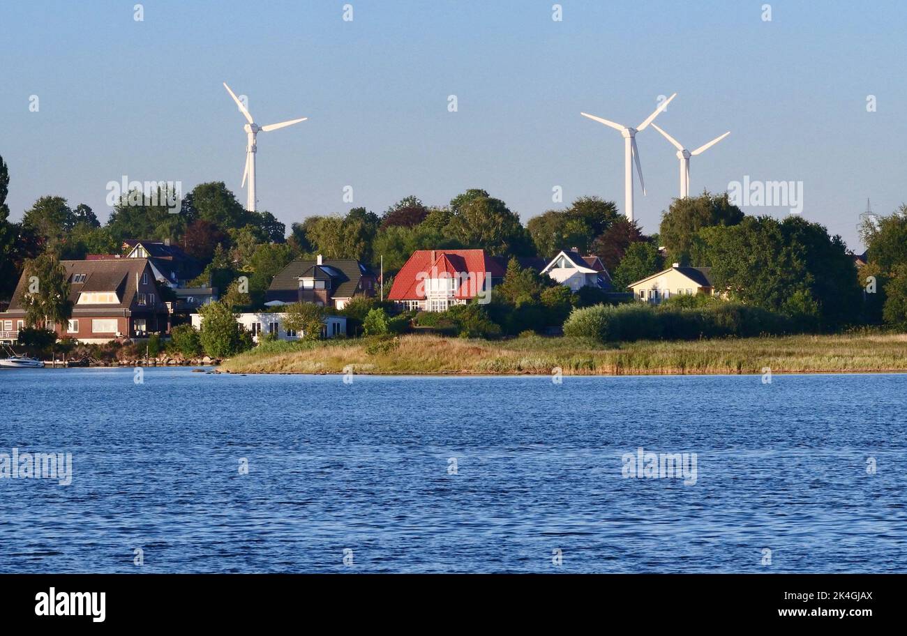 Kappeln, Germany. 12th Aug, 2022. 12.08.2022, Kappeln on the Schlei. Windmills for power generation stand behind residential houses near Kappeln. Credit: Wolfram Steinberg/dpa Credit: Wolfram Steinberg/dpa/Alamy Live News Stock Photo