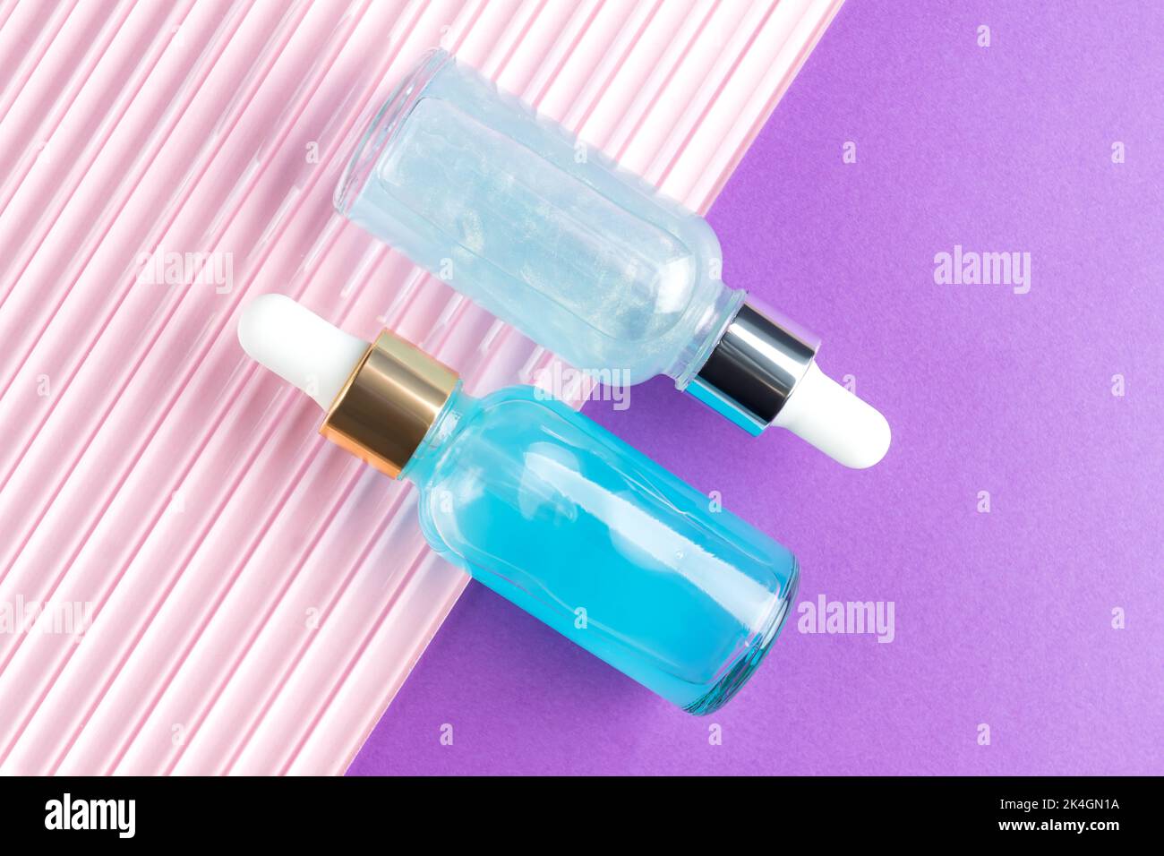 Cosmetic spa medical skincare, set of glass serum bottles with collagen and hyaluron on pink and purple background. medical product adverticement for Stock Photo
