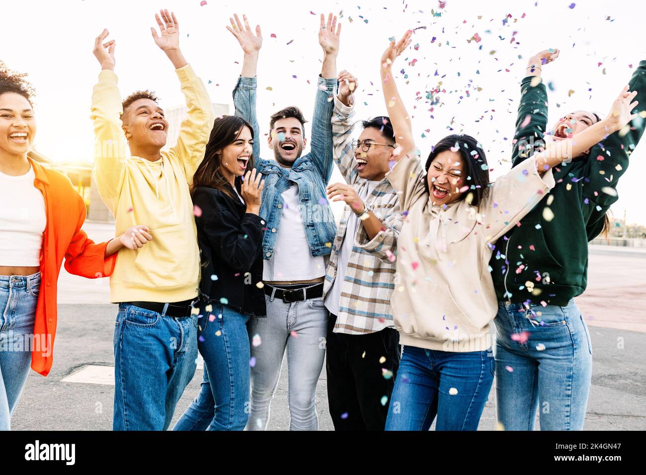 Group of diverse young friends celebrating together throwing confetti at party Stock Photo