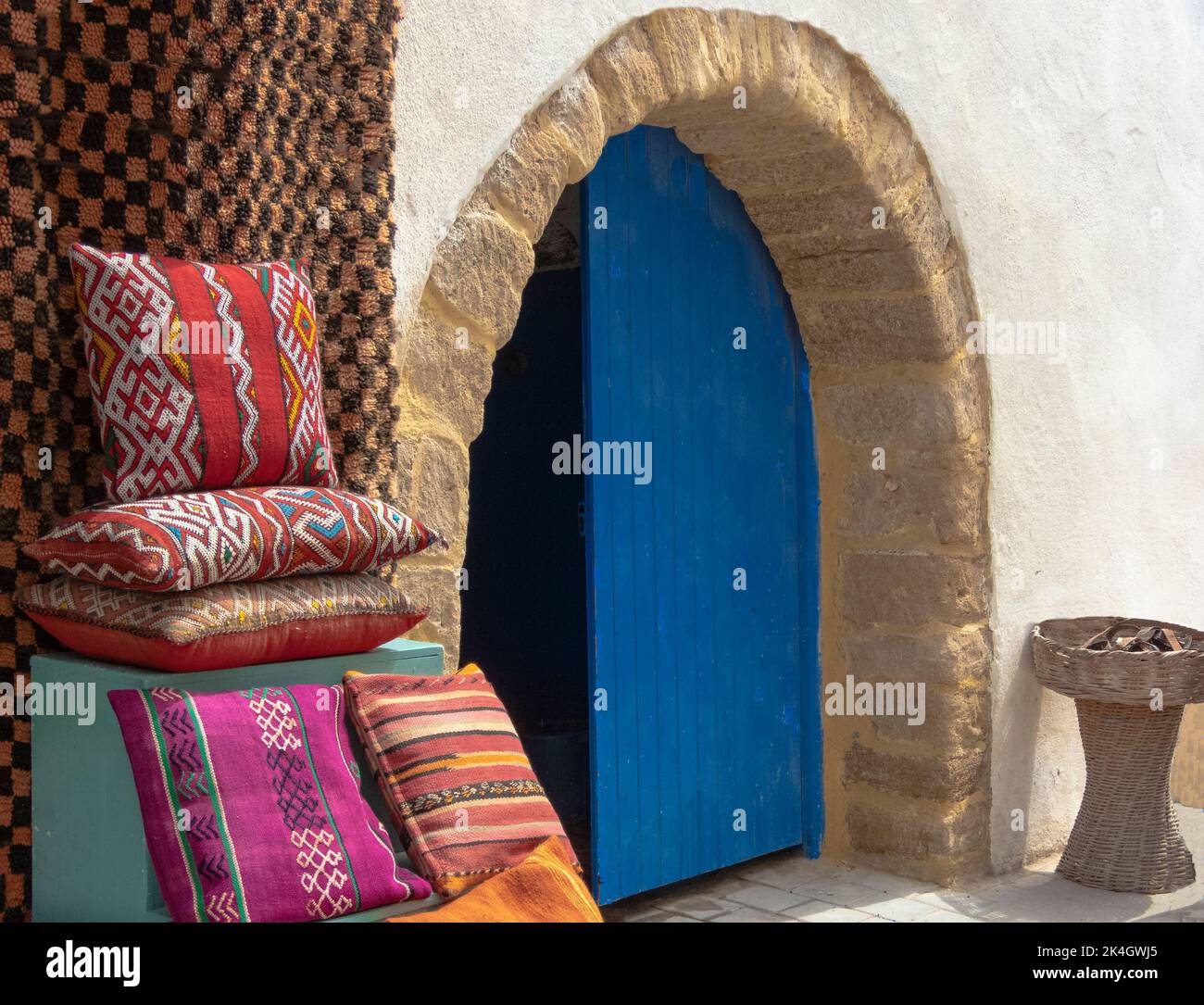 Arched doorway with a blue door and throws and cushions outside Stock