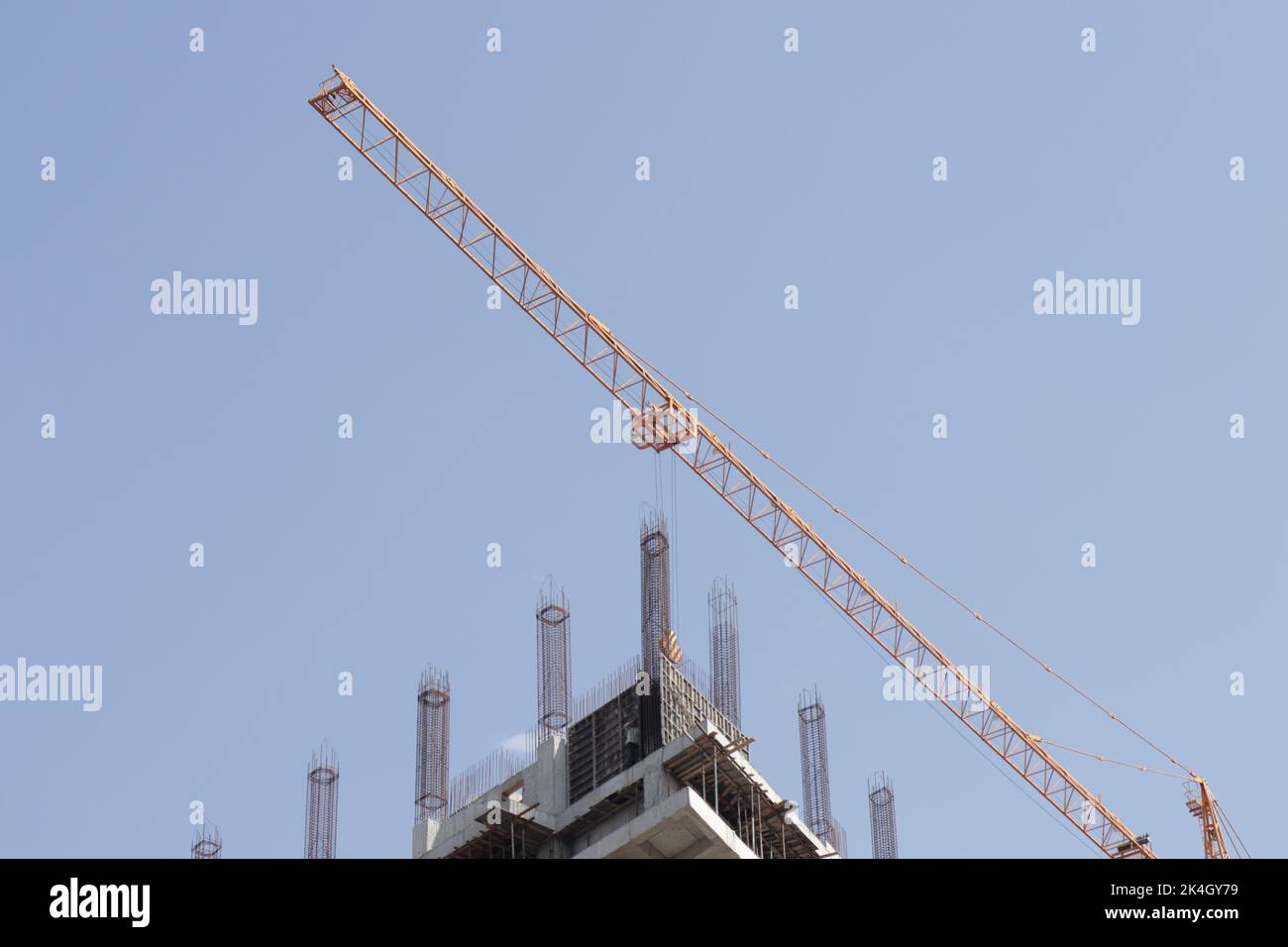 A low angle shot of a tall yellow crane over a building under ...