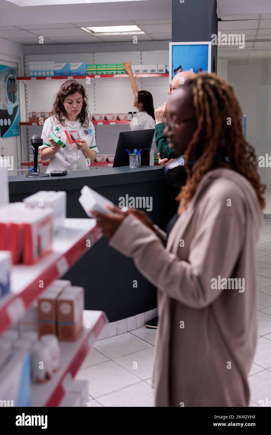 Pharmacy customers doing pharmaceutical shopping, buying vitamin
