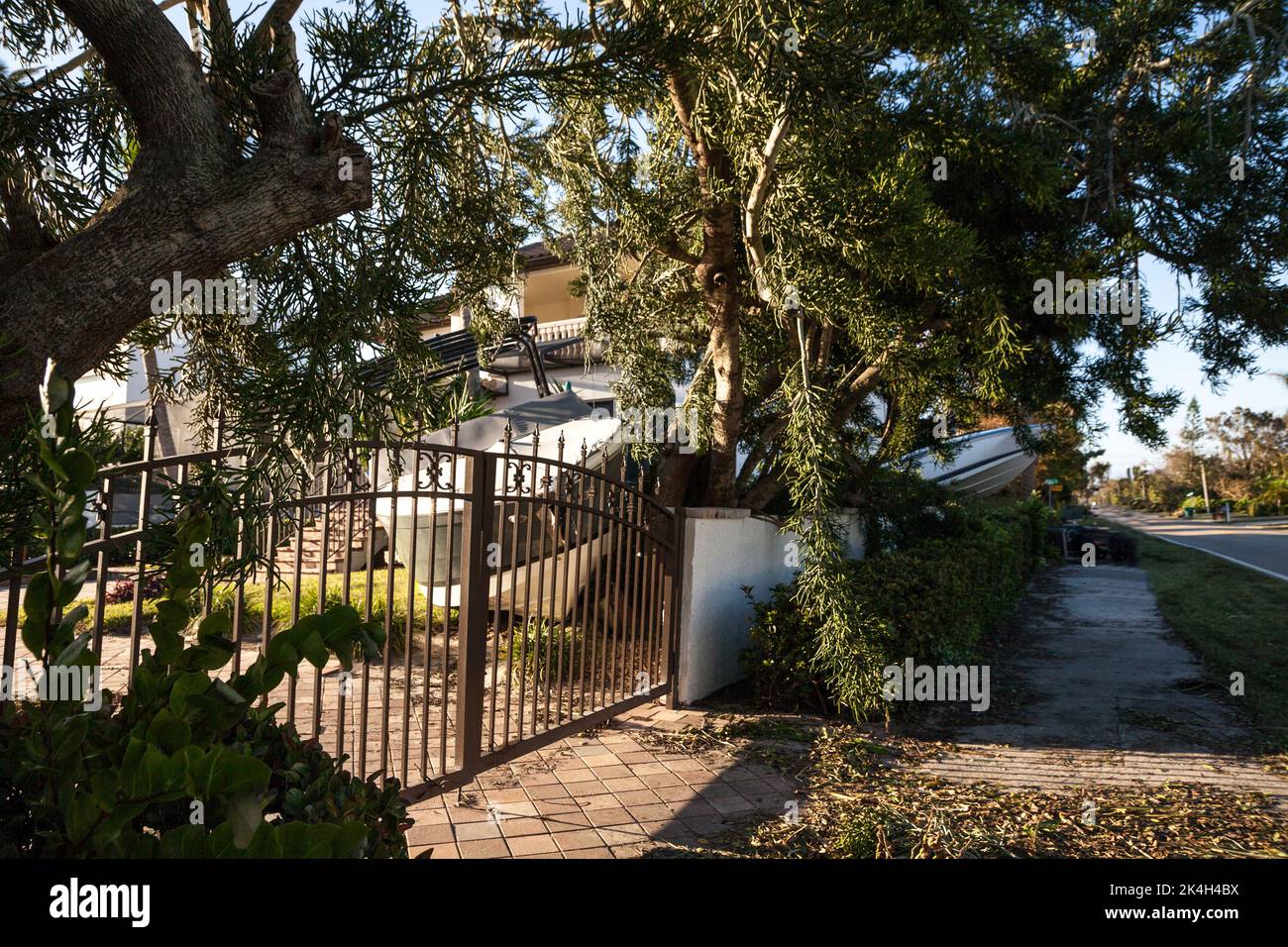 Naples, Florida, USA - September 28, 2022: NEWS – Boat wreck perched on land behind gates after storm surge flooding during Hurricane Ian in Naples, F Stock Photo