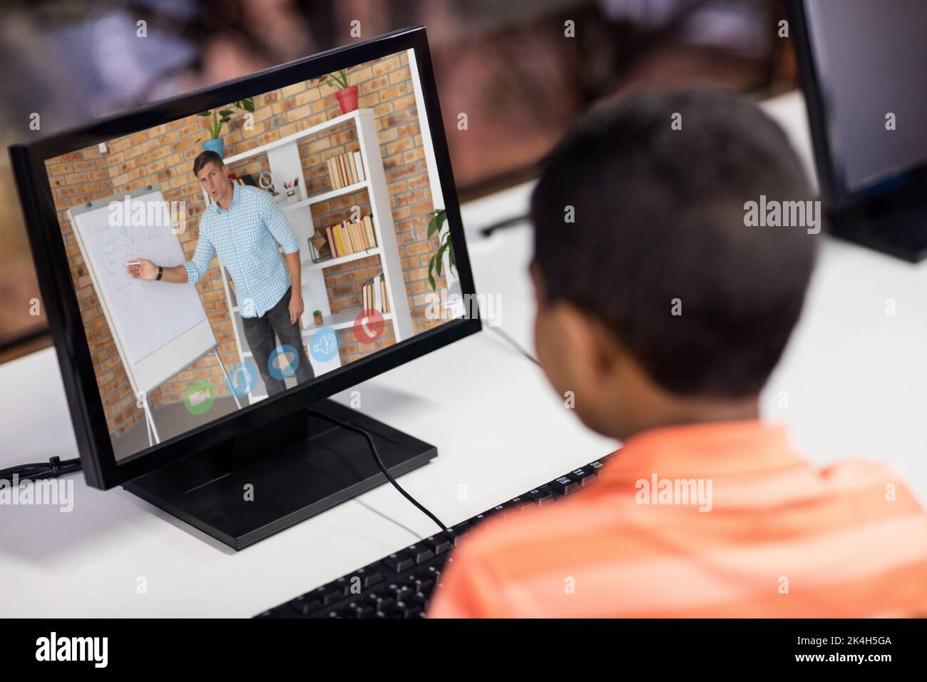 Mixed race schoolboy using computer on video call with male teacher ...