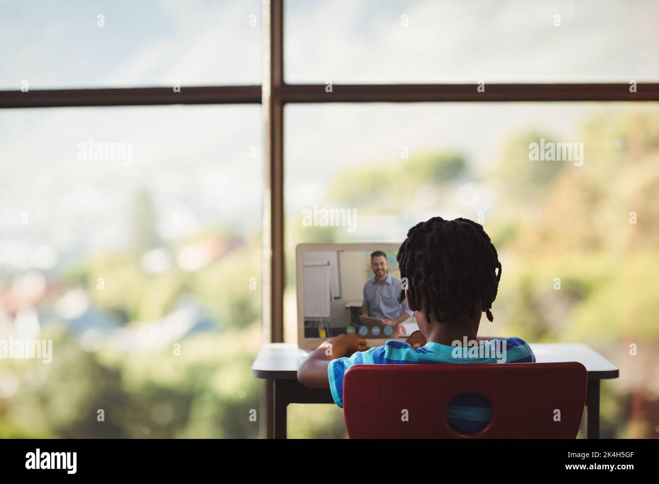 African american schoolboy using laptop on video call with male teacher ...